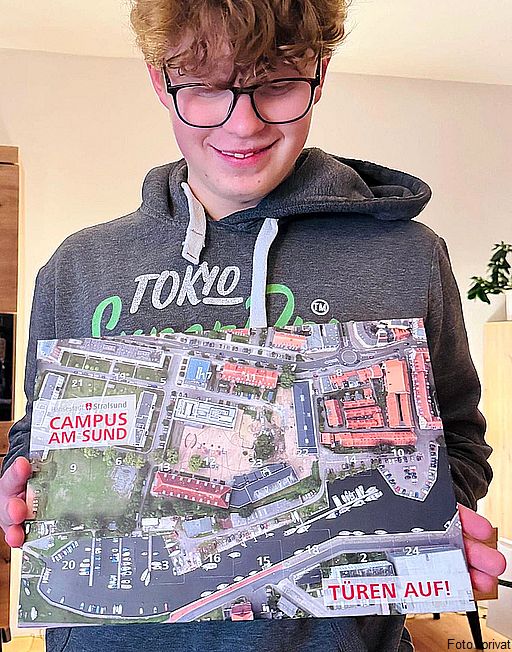 Stolz hält Niklas aus der 9. Klasse seinen Adventskalender mit dem Luftbild vom 'Campus am Sund' in die Kamera, den alle vom Oberbürgermeister bekommen haben, die bei der offiziellen Eröffnung mit dabei waren